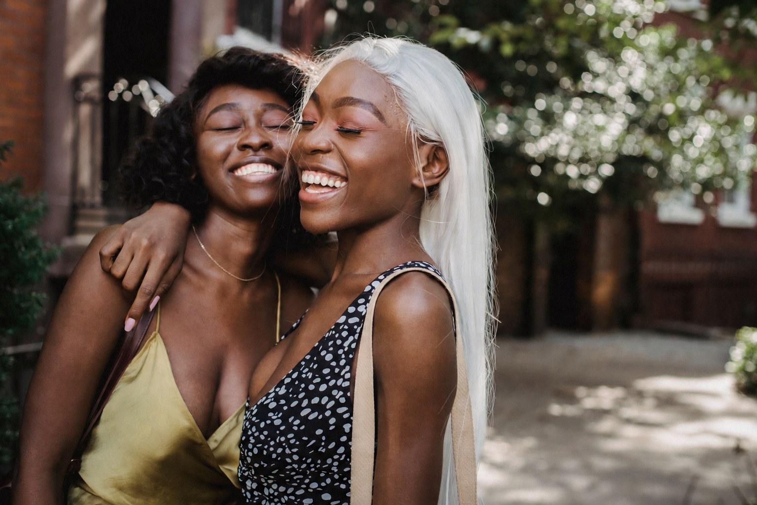 Two friends laughing together in warm sunlight